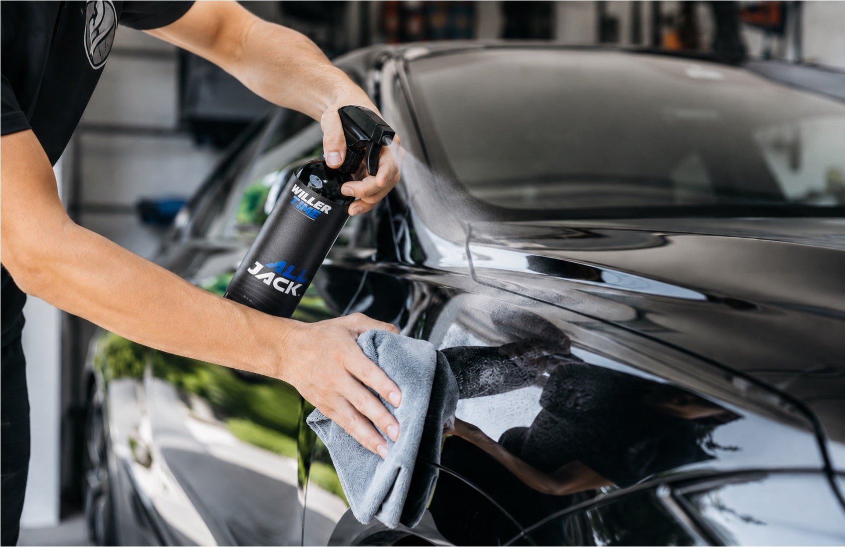 A person using All Jack Car Detail Spray to wipe down a car