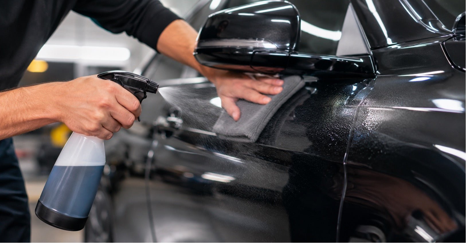 A person using a car detail spray to clean the exterior of a car