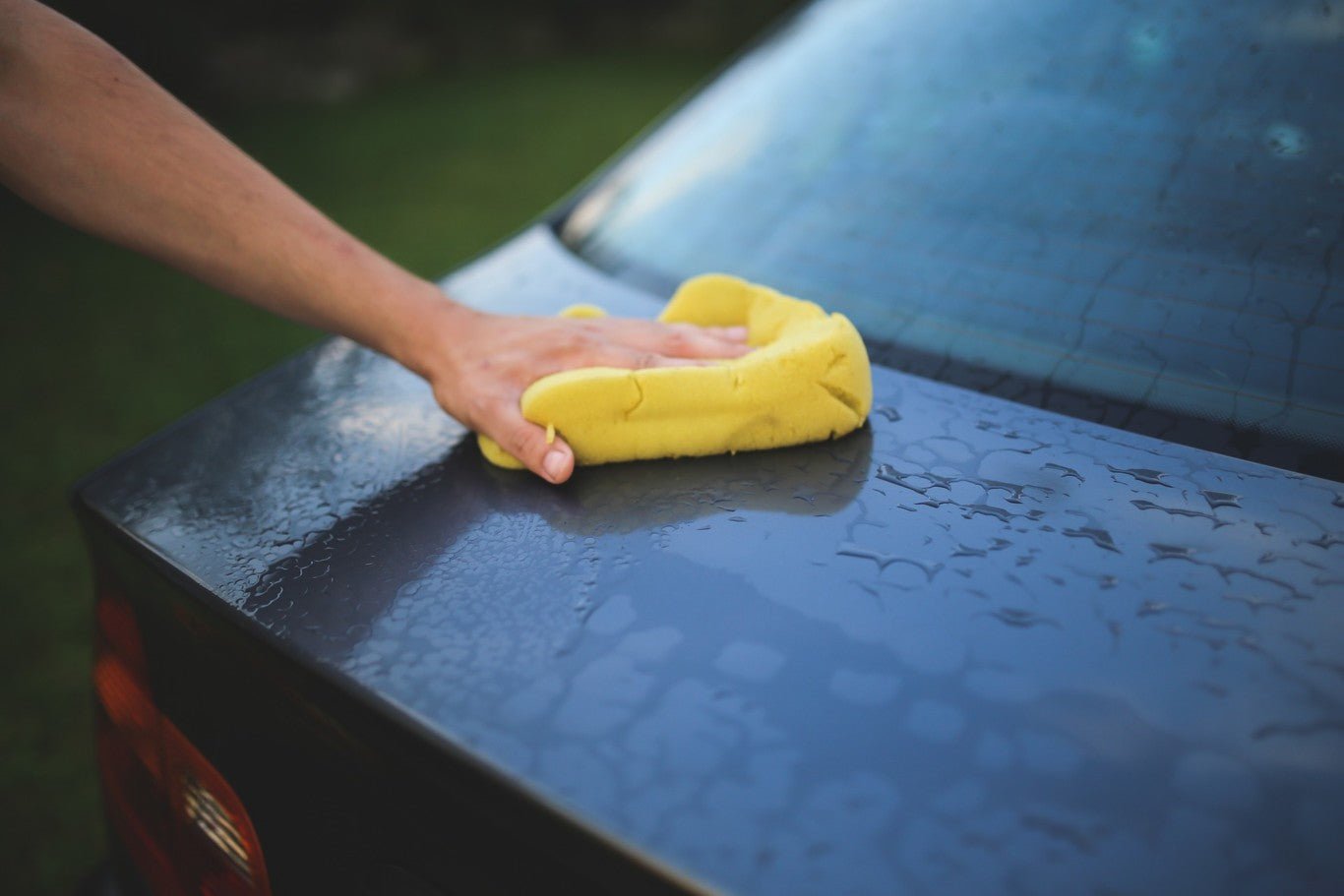 A person wiping a car after using a detail spray and waterless wash