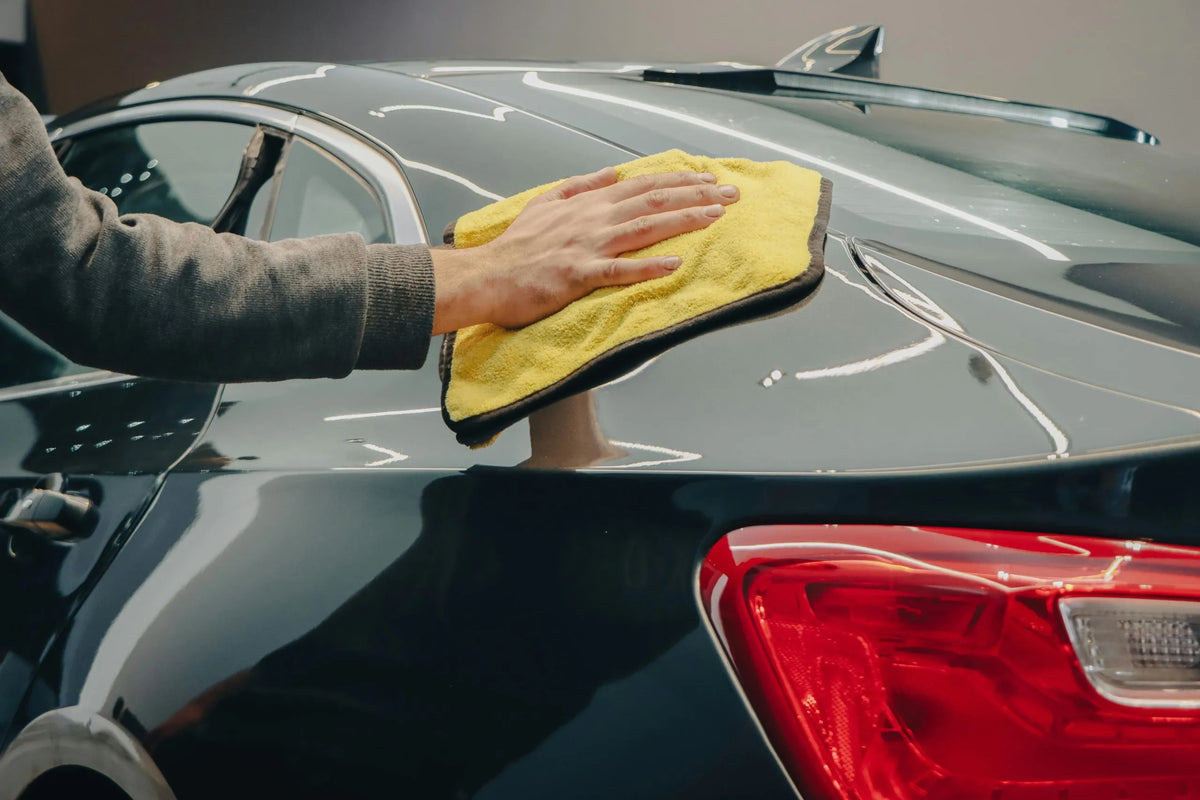 Man wiping his car with a microfiber cloth