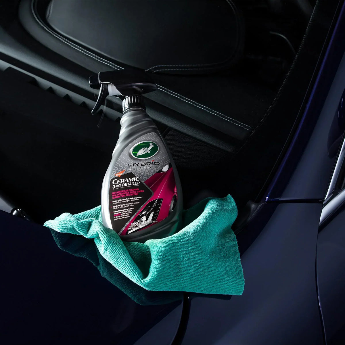 Turtle Wax Hybrid Solutions Ceramic 3-in-1 Detailer spray bottle with a microfiber cloth on a dark car hood